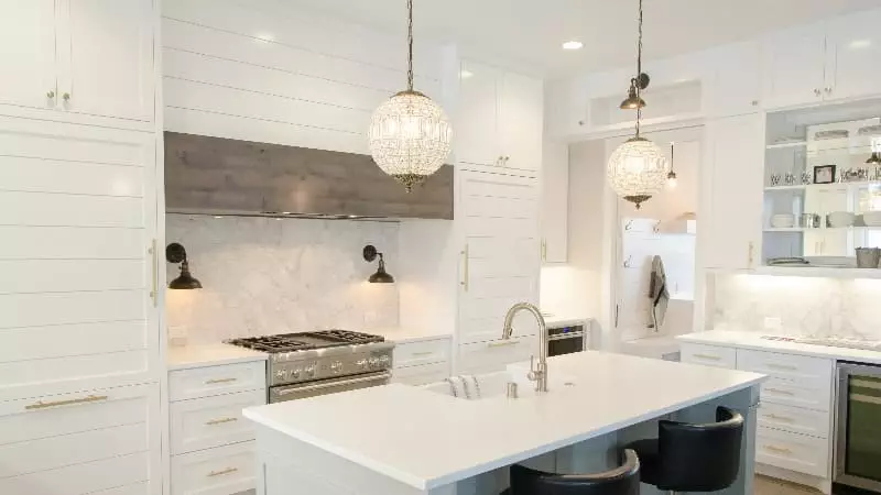 A beautiful white kitchen with two chandeliers